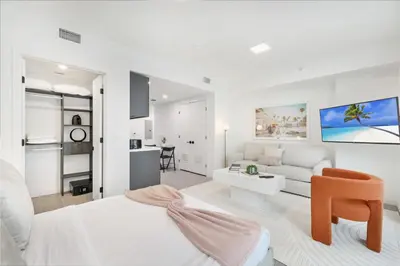a white living room with a white bed and a couch at Designer Studio Downtown Miami with Rooftop Pool and Gym in Miami