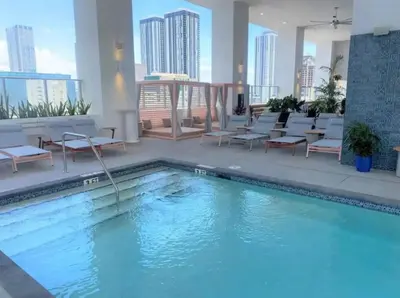 a swimming pool in a hotel with chairs and tables at Modern Luxe Studio in Downtown Miami with Rooftop Pool and Gym in Miami