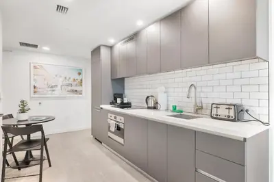 a white kitchen with a sink and a table at Modern Luxe Studio in Downtown Miami with Rooftop Pool and Gym in Miami