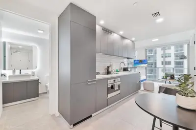 a kitchen with gray cabinets and a dining table at Modern Luxe Studio in Downtown Miami with Rooftop Pool and Gym in Miami