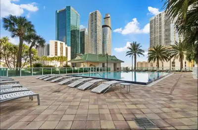 a swimming pool with lounge chairs and a city skyline at LOFT Brickell River 10 min To South Beach in Miami