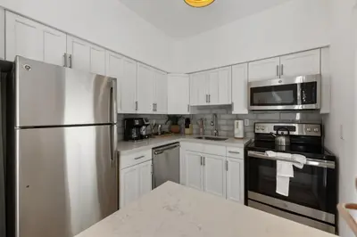 a kitchen with white cabinets and a stainless steel refrigerator at Lux Designer Apt 2BR and 2BA in the Heart of MIA Beach in Miami Beach