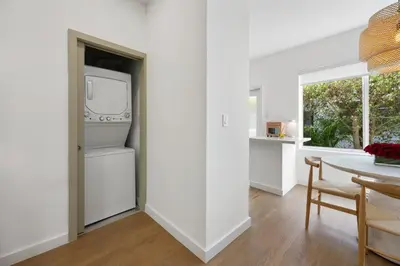 a kitchen with white walls and a table and a refrigerator at Lux Designer Apt 2BR and 2BA in the Heart of MIA Beach in Miami Beach