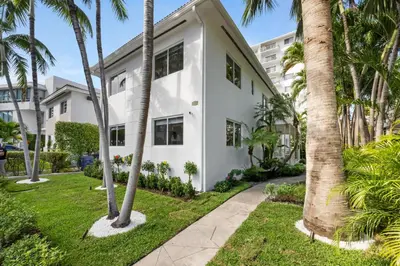 a white house with palm trees and a sidewalk at Lux Designer Apt 2BR and 2BA in the Heart of MIA Beach in Miami Beach