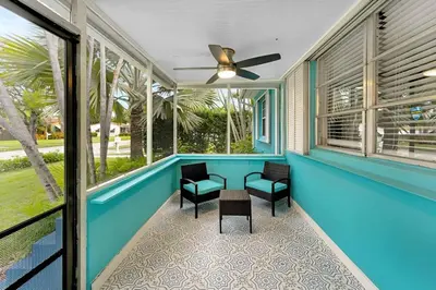 a screened porch with blue paint and chairs and a ceiling fan at The Palm House in Hollywood