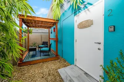 a door to a patio with a blue house at Ocean Breeze Home in Hollywood