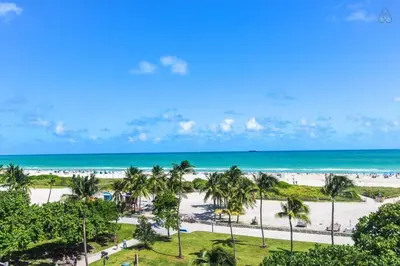 a view of a beach with palm trees and the ocean at Oceanfront Oasis 2-BR Apartment on Ocean Drive in Miami Beach