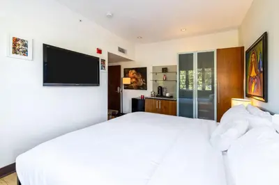 a bedroom with a white bed and a flat screen tv at Oceanfront Oasis 2-BR Apartment on Ocean Drive in Miami Beach