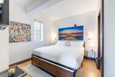 a bedroom with a white bed and a painting on the wall at Oceanfront Oasis 2-BR Apartment on Ocean Drive in Miami Beach