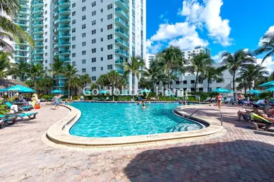 a swimming pool in a resort with palm trees and buildings at Hollywood Beach, 10th floor, on the beach 10T in Hollywood
