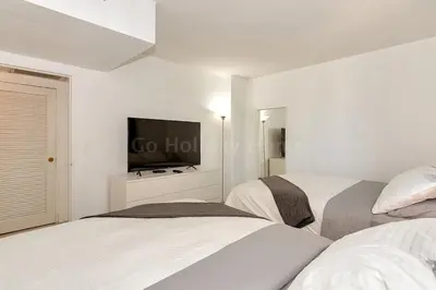 a white bedroom with two beds and a flat screen tv at Hollywood Beach, 10th floor, on the beach 10T in Hollywood