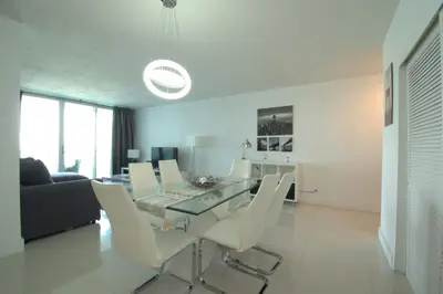 a dining room with a glass table and white chairs at Hollywood Beach, 10th floor, on the beach 10T in Hollywood