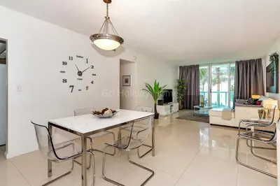a living room with a table and chairs and a clock on the wall at Ocean front, full equiped, pool and parking 2M in Hollywood