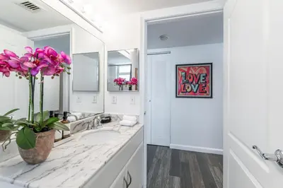 a white bathroom with a sink and a vase of flowers at Brickell 2 bedroom condo in the heart of Miami in Miami