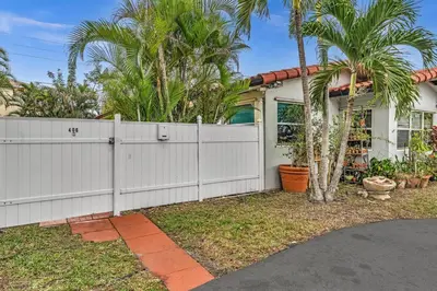 a white fence in front of a house with palm trees at Hollywood Beach & Casino Heated Pool House in Hollywood