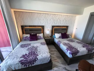 two beds in a hotel room with purple and white sheets at 2b 2b Beautiful Apmt in Hallandale Beach with beach service in Hallandale Beach