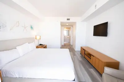 a white bedroom with a large bed and a television at 2B 2B Beachfront Pool Gym, and Restaurant in Hallandale Beach