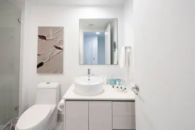 a bathroom with a sink and a toilet and a mirror at 2B 2B Beachfront Pool Gym, and Restaurant in Hallandale Beach
