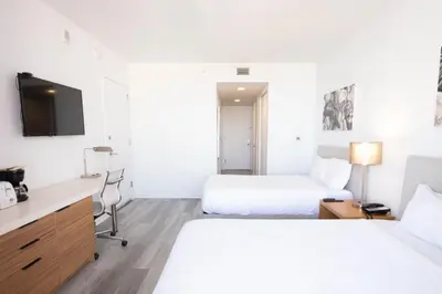 a hotel room with two beds and a desk at 2B 2B Beachfront Pool Gym, and Restaurant in Hallandale Beach