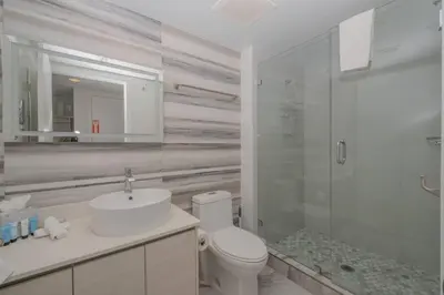 a bathroom with a toilet and a sink and a shower at Steps from the beach 2B 2B Pool, Gym, and More in Hallandale Beach