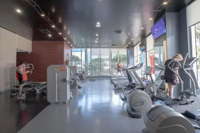 a gym with several people exercising on tread machines at Apartment in Miami Beach with Kitchen, Beach Service and Gym in Hallandale Beach