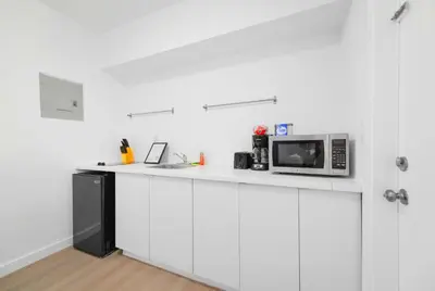 a white kitchen with a microwave and a sink at Stylish Studio Near Miami Relevant Spots in Miami