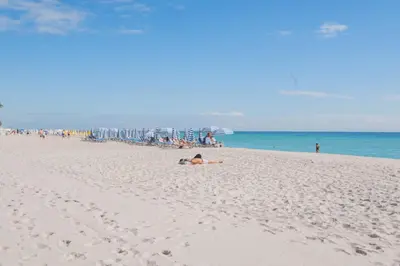 a group of people on a beach with an umbrella at Beautiful Studio in Hallandale with Beach & Pool in Hallandale Beach