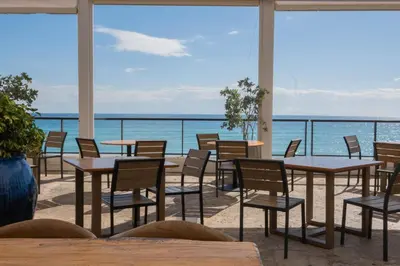 a patio with tables and chairs and the ocean at Beautiful Studio in Hallandale with Beach & Pool in Hallandale Beach