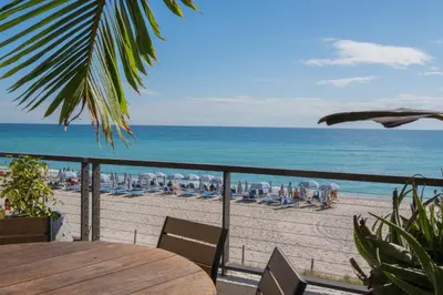 a view of a beach with a wooden table and chairs at Beautiful Studio in Hallandale with Beach & Pool in Hallandale Beach