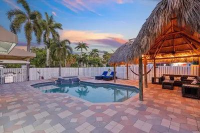 a swimming pool with a straw umbrella and a resort at Blue Wave Retreat at Hollywood Beach home in Hollywood