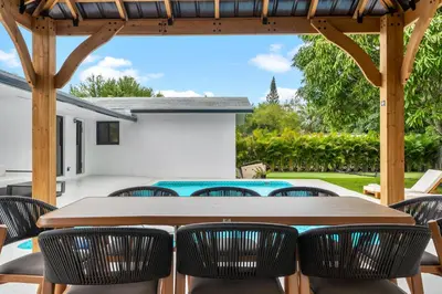 a wooden table and chairs under a wooden pergola at Modern Luxury Home with Racket Sports Gym BBQ in Rockdale