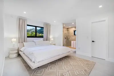 a white bedroom with a large bed and a window at Modern Luxury Home with Racket Sports Gym BBQ in Rockdale