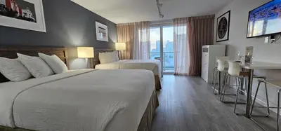 a hotel room with two beds and a table with a bar at City view with balcony on the Beach in Sunny Isles Beach