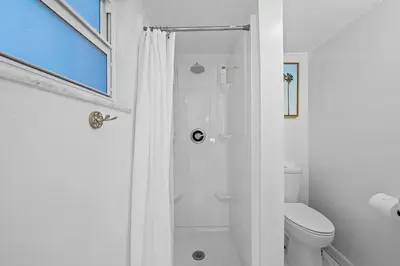 a white bathroom with a shower and a toilet at Beach Home in Victoria Park in Fort Lauderdale