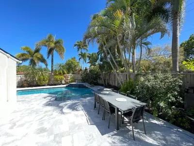 a patio with a table and chairs next to a swimming pool at La Dolce Villa in Fort Lauderdale