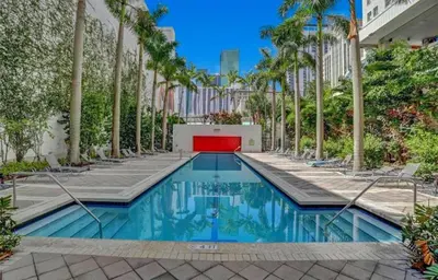 a swimming pool with palm trees and a building at Fully Equipped Modern Loft in the heart of Miami in Miami