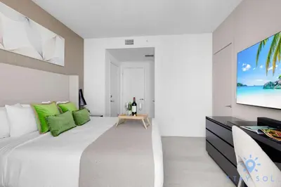 a white bedroom with a large bed with green pillows at Bay View 2Br Apartment with Amenities in Hollywood