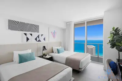 two beds in a room with a view of the ocean at Bay View 2Br Apartment with Amenities in Hollywood