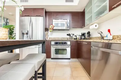 a kitchen with wooden cabinets and stainless steel appliances at BrickellRiver LOFT with parking & 12 min to South Beach in Miami