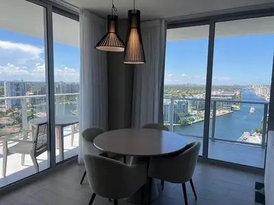 a dining room with a table and chairs and a large window at Beachfront Apt with Gym, Pool, and Rest in Miami in Hollywood