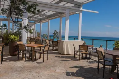 a patio with tables and chairs and the ocean at Studio 2b 1b with Beach and Pool Miami Beach in Hallandale Beach