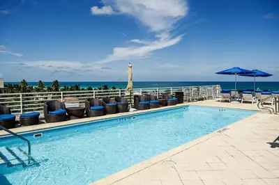 a swimming pool with chairs and an umbrella and the ocean at Studio with rooftop pool on Ocean Dr B303 in Miami Beach
