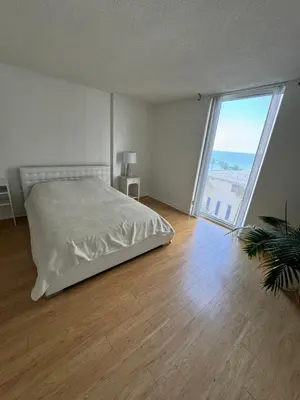 a white bedroom with a bed and a large window at beautiful place 1 in Hollywood