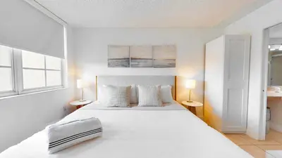 a white bedroom with a large bed and two lamps at Modern Luxury Condo Near Beach & Aventura Mall in Aventura