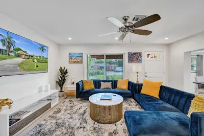 a living room with a blue couch and a ceiling fan at Private Room in Spacious 3-Bedroom Home in Fort Lauderdale