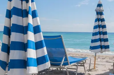 two beach chairs and umbrellas on the beach at Studio Apmt 2 Beds with pool and gym in Hallandale Beach