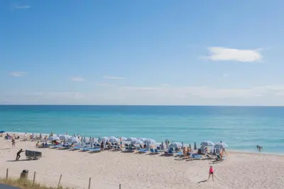 a group of people on a beach with chairs and umbrellas at Studio Apmt 2 Beds with pool and gym in Hallandale Beach