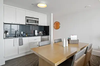 a kitchen with white cabinets and a wooden table at Beachfront Ritz-Carlton Luxury 1BR Residence in Fort Lauderdale