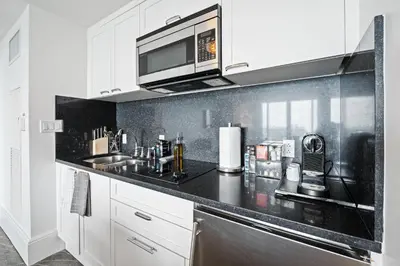 a kitchen with white cabinets and a black counter top at Beachfront Ritz-Carlton Luxury 1BR Residence in Fort Lauderdale