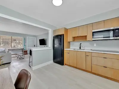 a kitchen with wooden cabinets and a black refrigerator at North Hollywood Beach 1BR | Walk to Ocean in Dania Beach